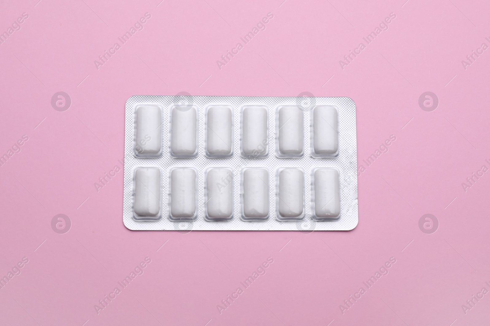 Photo of Blister with chewing gums on pink background, top view