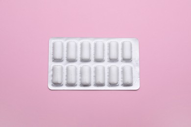 Photo of Blister with chewing gums on pink background, top view