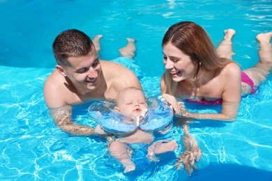 Happy parents with little baby in swimming pool on sunny day, outdoors