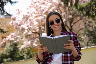 Happy young woman reading book in park