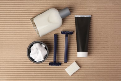 Photo of Razors, shaving foam, soap, cream and aftershave on cardboard, flat lay