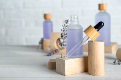 Bottles of lavender essential oil and flowers on wooden table. Space for text