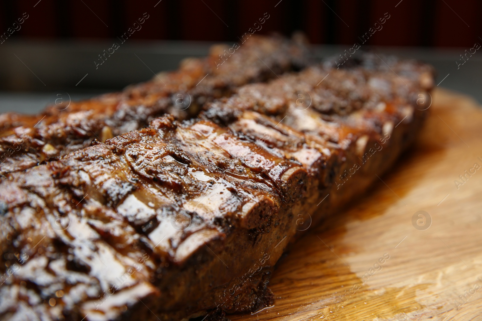 Photo of Tasty grilled pork ribs on wooden board, closeup