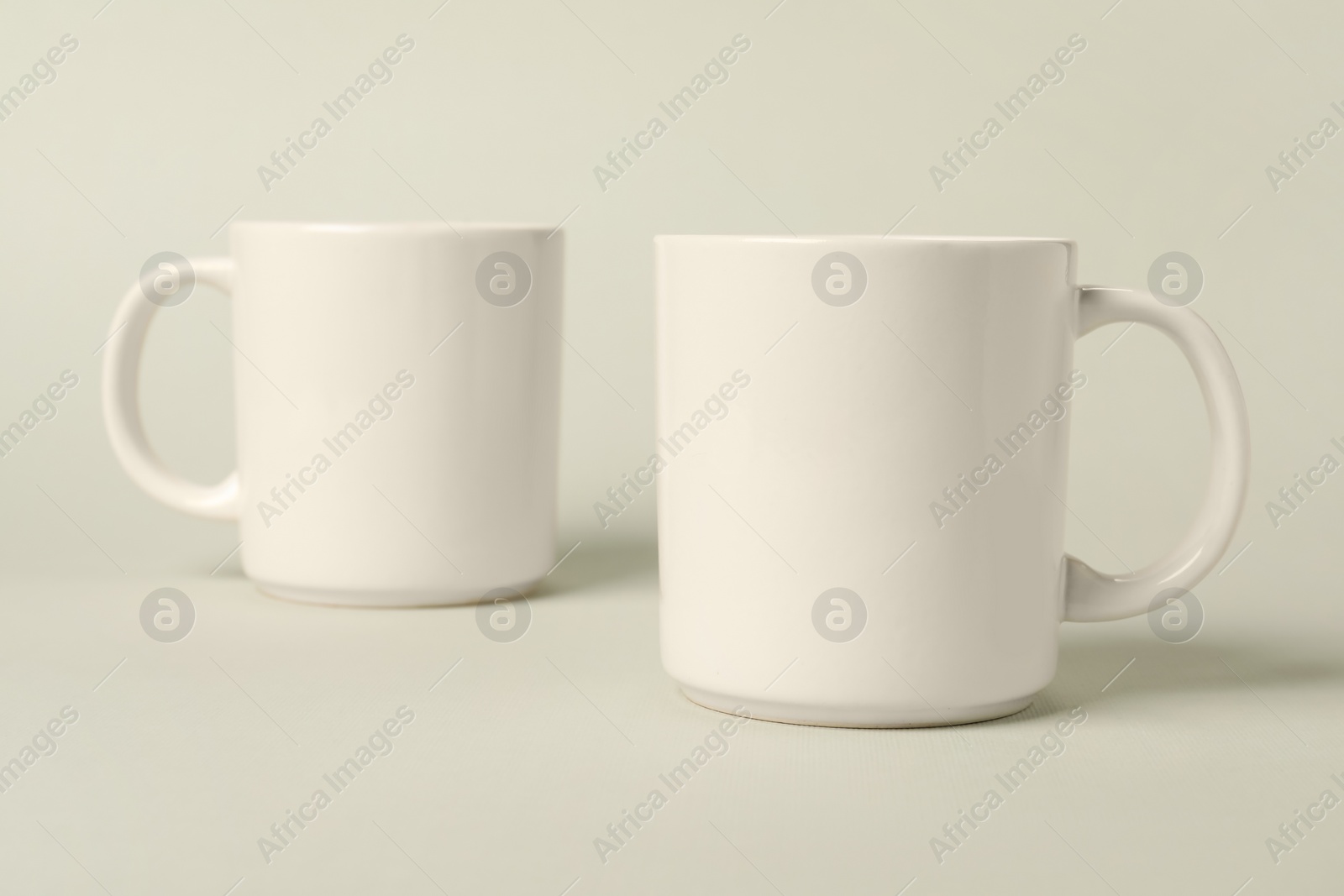 Photo of Two white ceramic mugs on light grey background