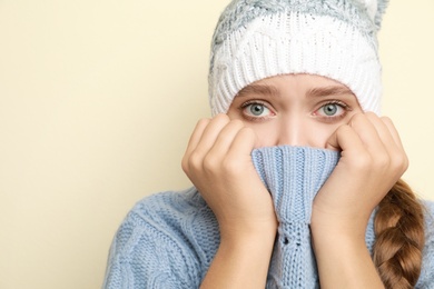 Young woman wearing hat suffering from fever on light background, space for text. Cold symptoms