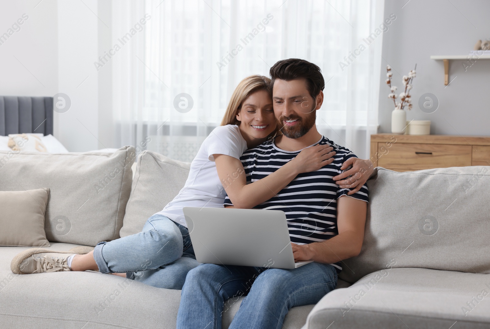 Photo of Happy couple with laptop on sofa at home