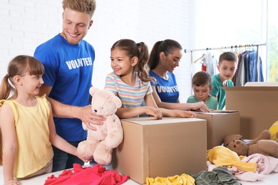 Volunteers with children sorting donation goods indoors