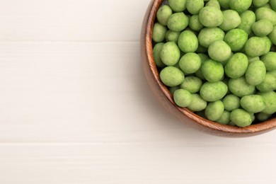 Photo of Bowl with tasty wasabi coated peanuts on white wooden table, top view. Space for text