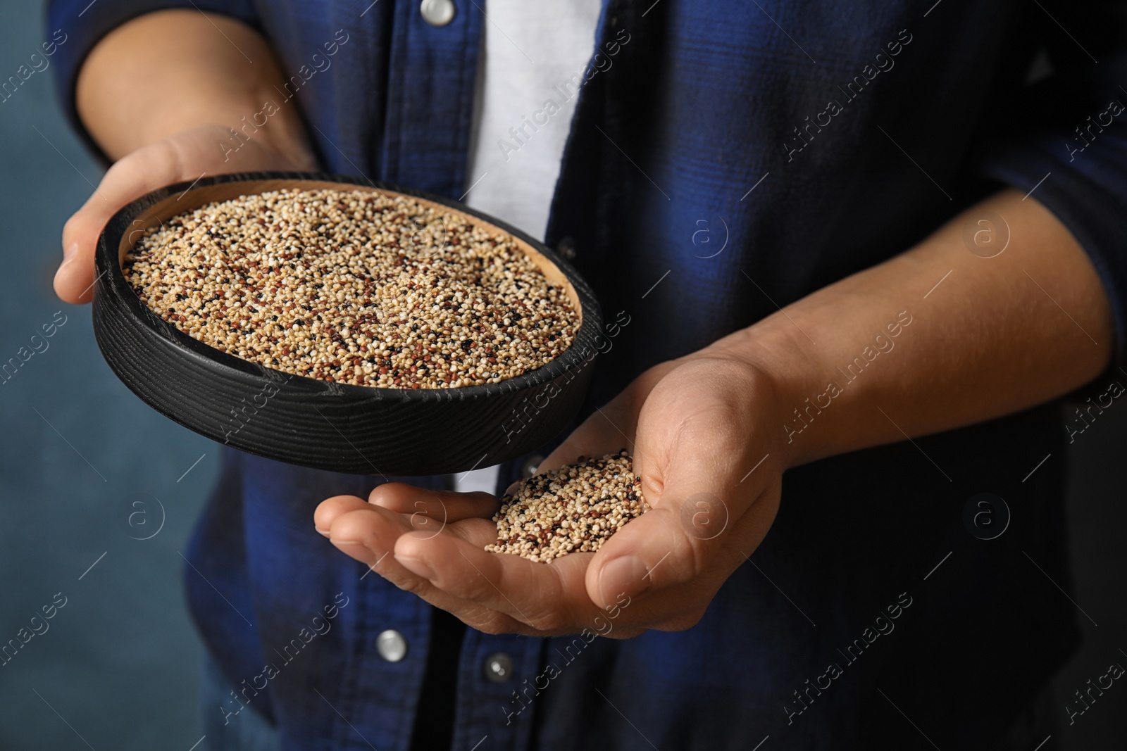 Photo of Woman holding plate with mixed quinoa seeds on color background, closeup