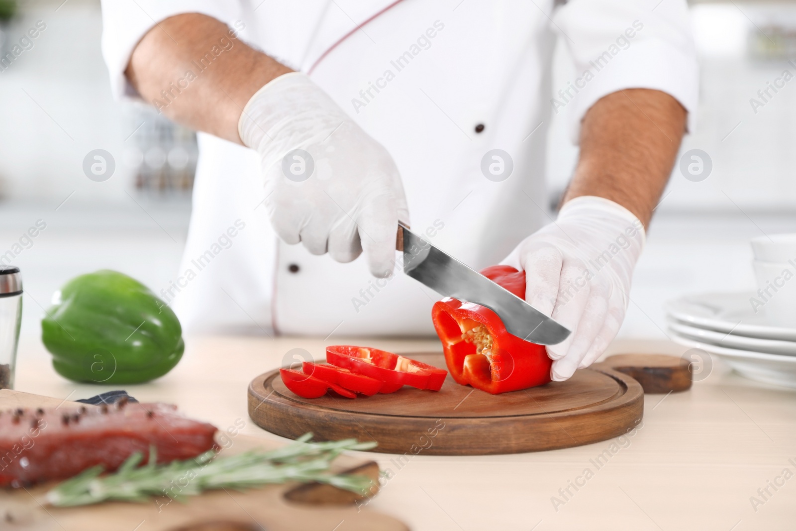 Photo of Professional chef cutting pepper on table in kitchen, closeup