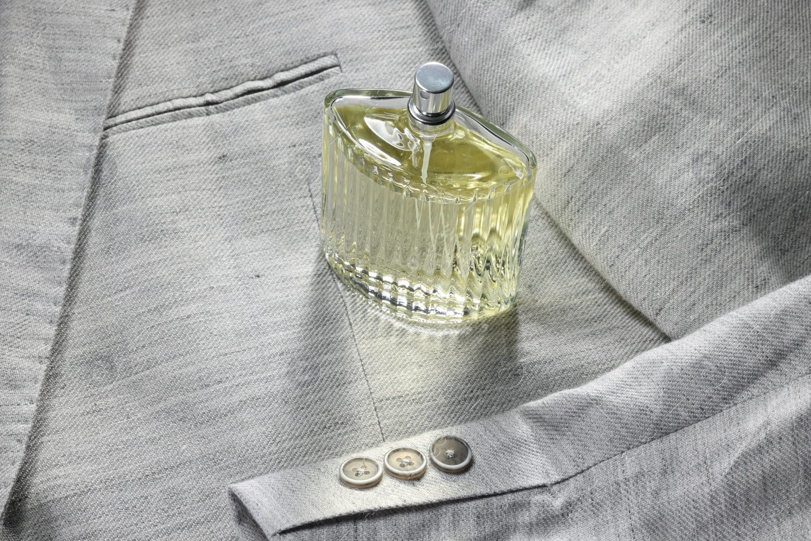 Photo of Luxury men's perfume in bottle on grey jacket