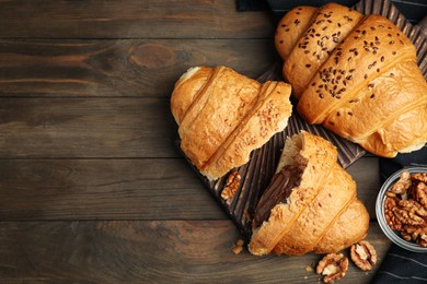 Photo of Flat lay composition with tasty croissants and walnuts on wooden table. Space for text