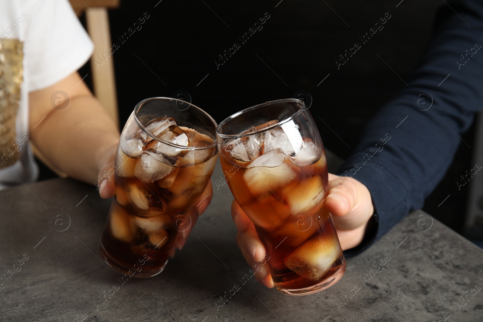 Photo of Friends with glasses of tasty refreshing cola at table, closeup view