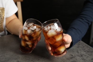 Friends with glasses of tasty refreshing cola at table, closeup view