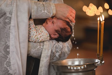 Priest baptizing adorable baby in church, closeup