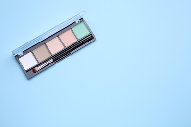 Contouring palette with brush on light blue background, top view and space for text. Professional cosmetic product