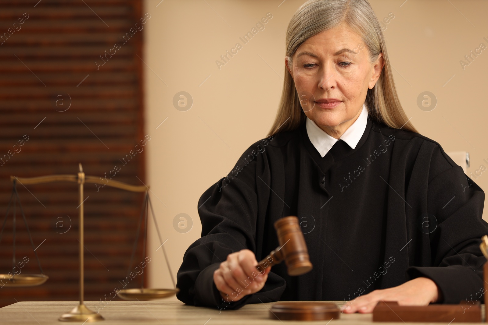 Photo of Judge striking mallet at wooden table indoors