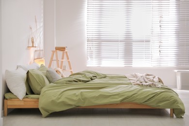 Photo of Comfortable bed with olive green linen in modern room interior