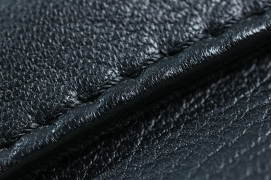 Black leather with seam as background, closeup