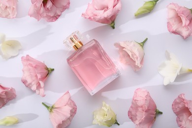 Luxury perfume and floral decor on white background, flat lay