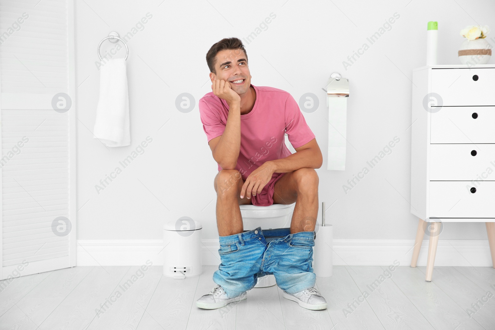 Photo of Young man sitting on toilet bowl at home