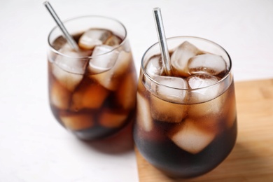 Photo of Glasses of tasty cola with ice cubes on white table, closeup