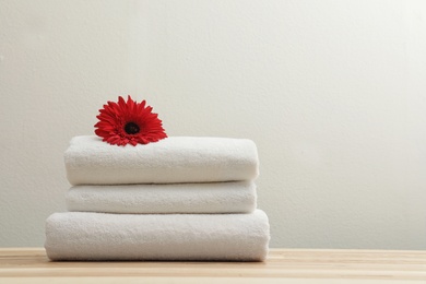 Photo of Stack of fresh towels with flower on table. Space for text