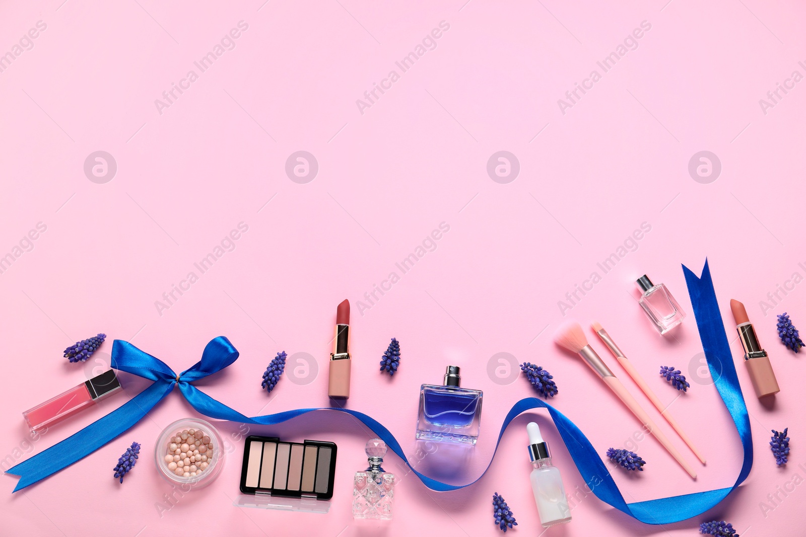 Photo of Flat lay composition with different makeup products and beautiful spring flowers on pink background. Space for text