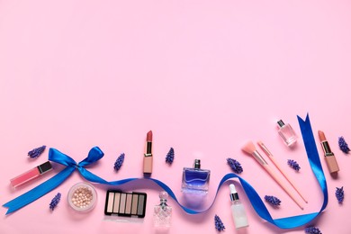 Flat lay composition with different makeup products and beautiful spring flowers on pink background. Space for text