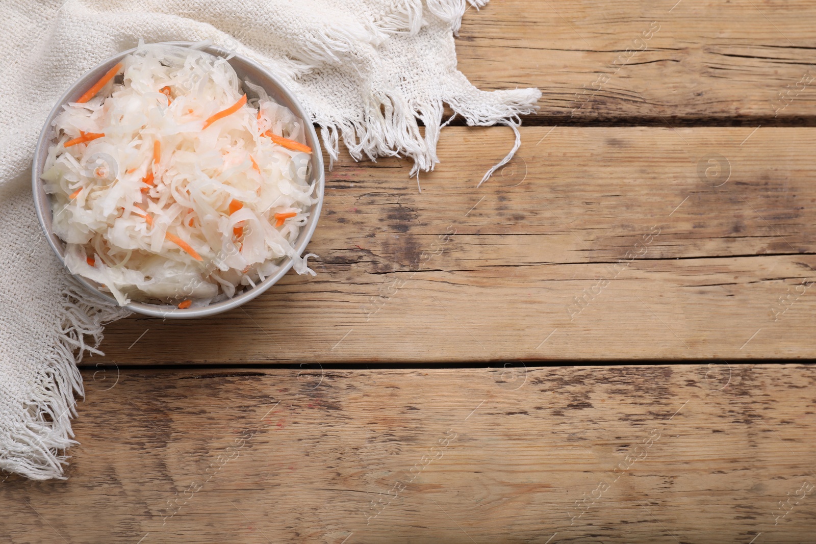 Photo of Bowl of tasty sauerkraut on wooden table, flat lay. Space for text