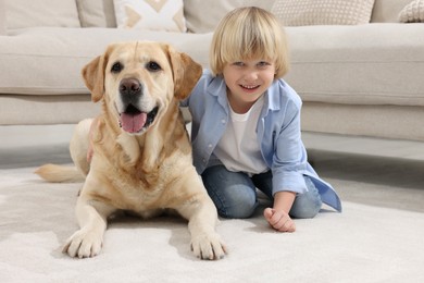 Cute little child with Golden Retriever on floor at home. Adorable pet