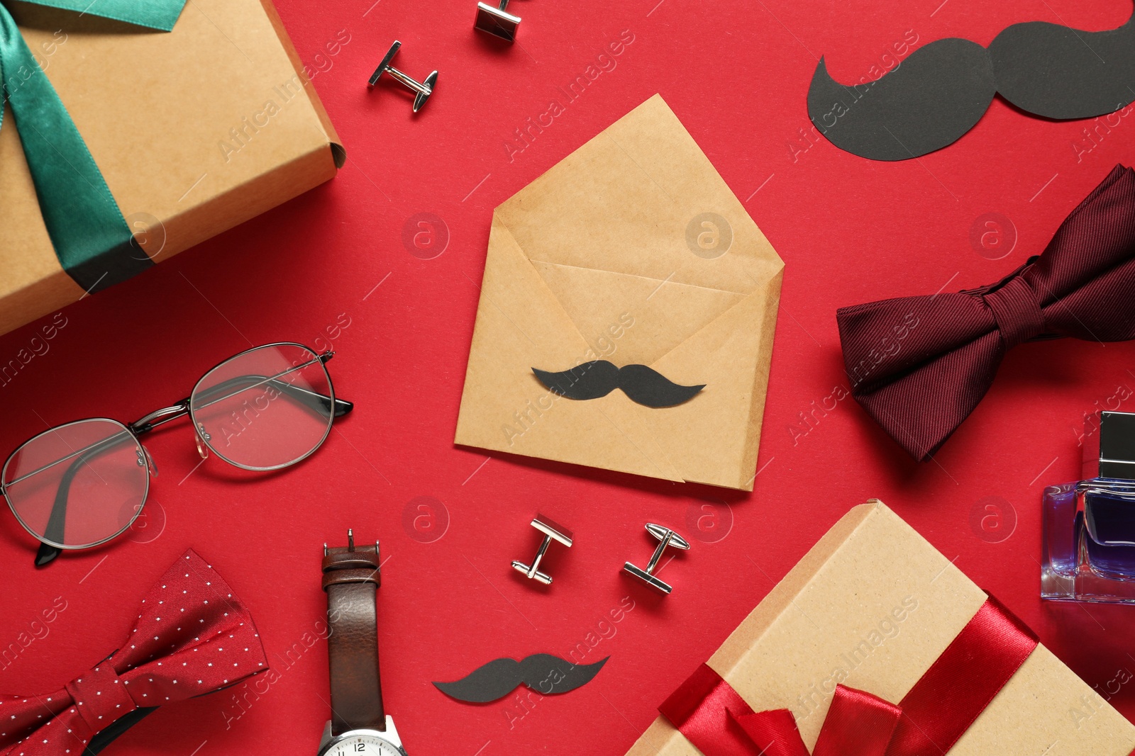 Photo of Paper mustache, gift boxes and men accessories on red background, flat lay. Father's day celebration