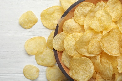 Delicious crispy potato chips in bowl on table, top view with space for text