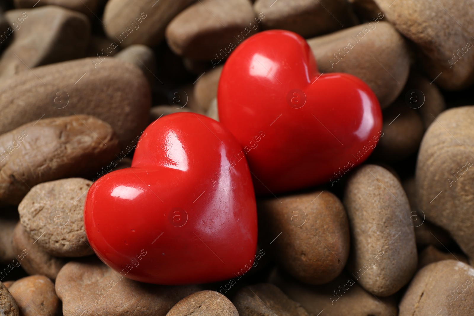 Photo of Red decorative hearts on stones, closeup view