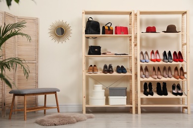 Photo of Wooden shelving unit with different shoes and accessories in stylish room interior