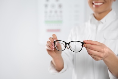 Female ophthalmologist with eyeglasses in clinic, closeup. Space for text