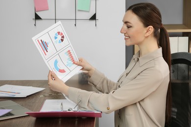 Photo of Businesswoman working with charts at wooden table in office