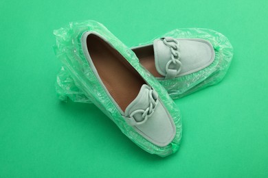 Women's mules in shoe covers on green background, closeup