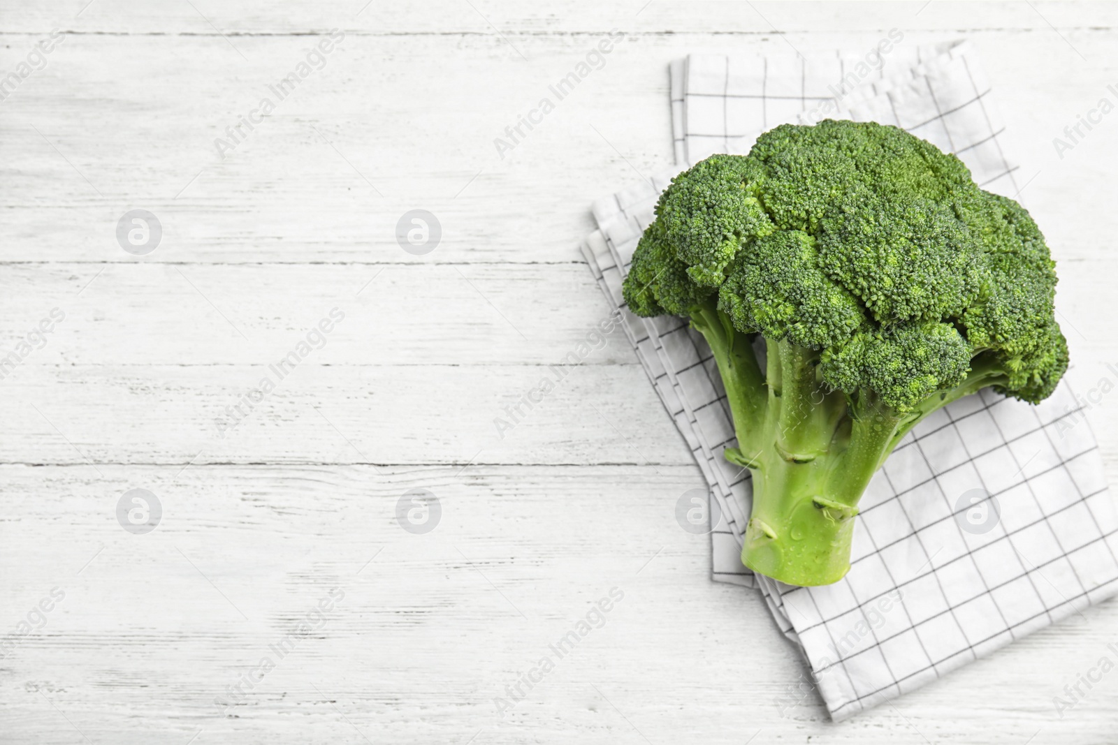 Photo of Fresh green broccoli on white wooden table, top view. Space for text