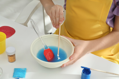 Little girl making homemade slime toy at table, closeup