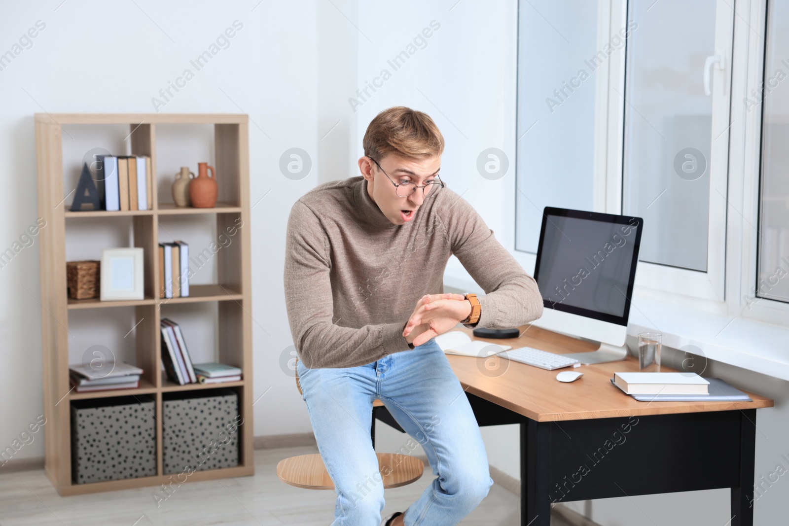 Photo of Emotional young man checking time in office. Being late