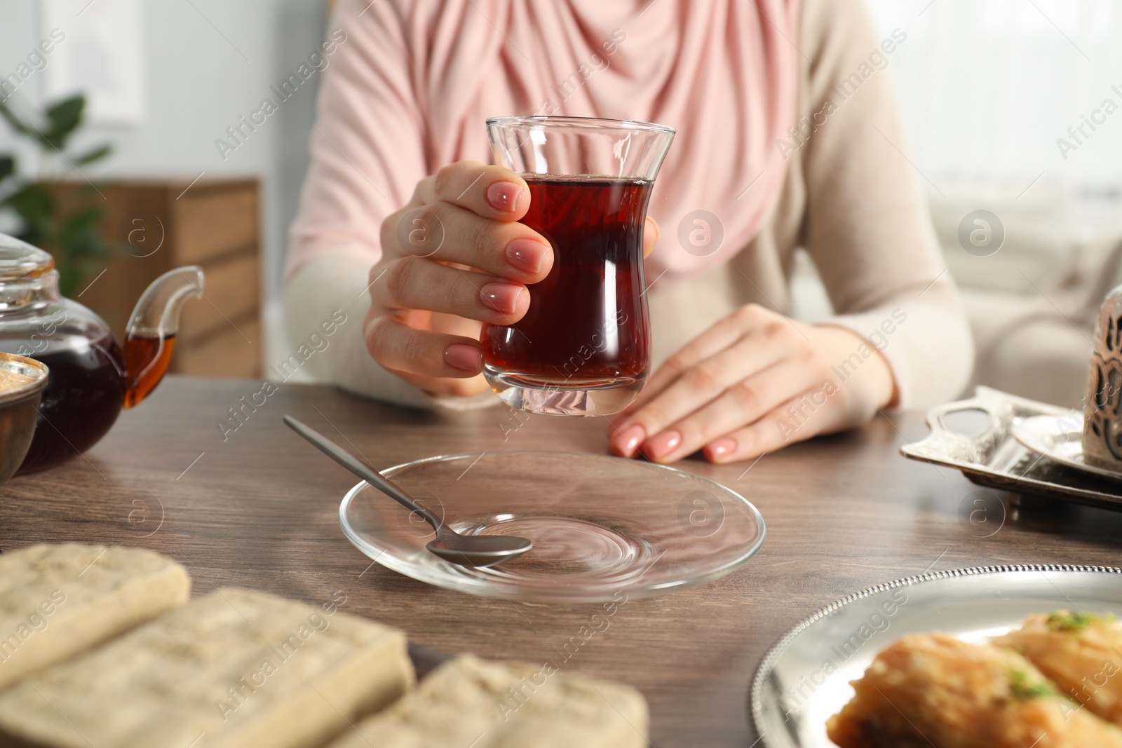 Photo of Woman with cup of delicious Turkish tea at wooden table, closeup