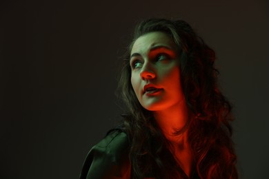 Portrait of beautiful young woman on dark background with neon lights