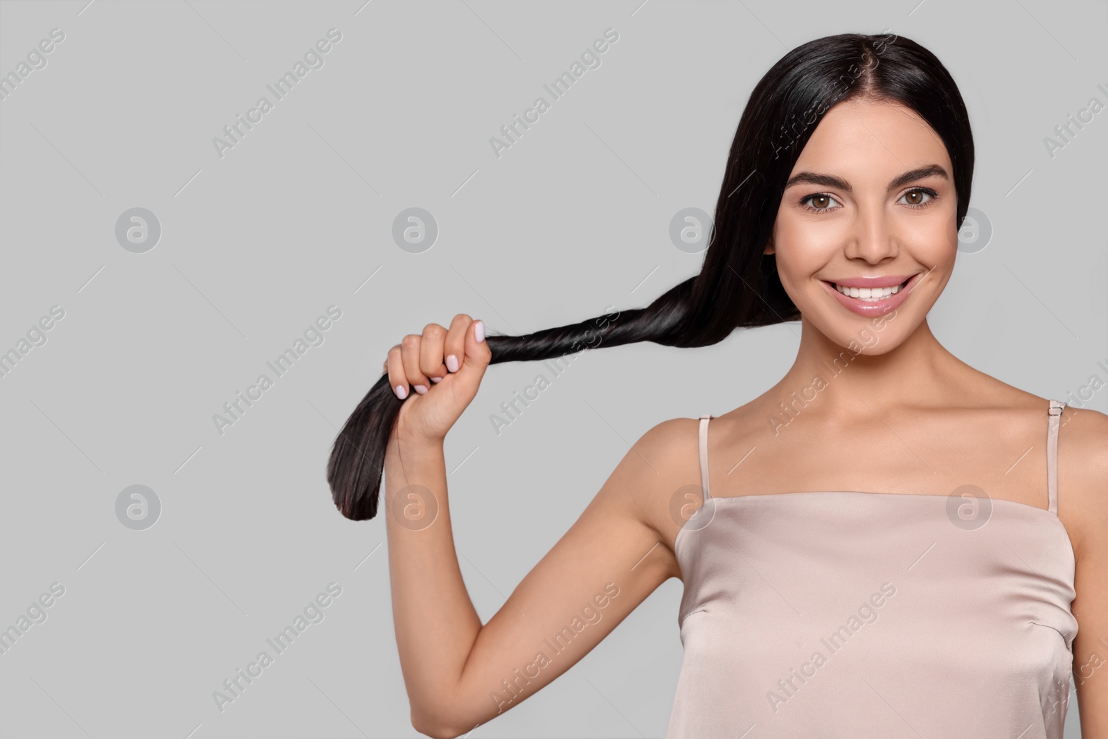 Photo of Portrait of beautiful young woman with healthy strong hair on light grey background, space for text