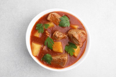 Photo of Delicious goulash in bowl on light grey table, top view