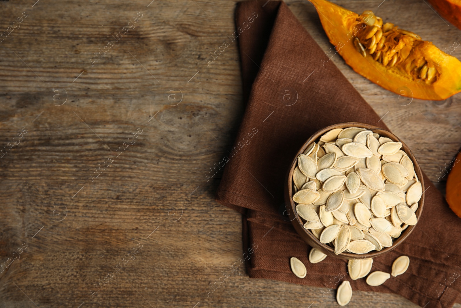 Photo of Flat lay composition with raw pumpkin seeds on wooden table, space for text