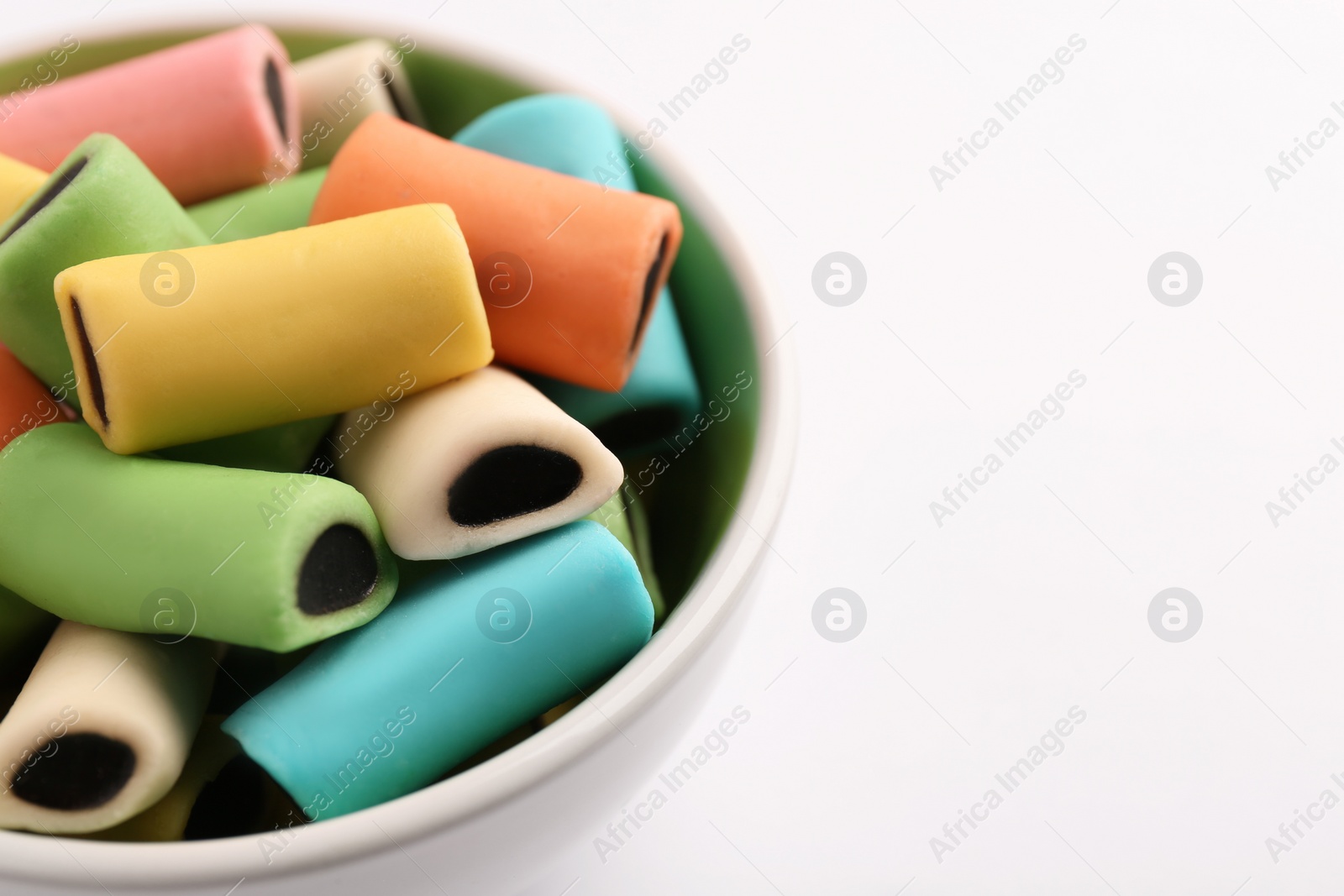 Photo of Bowl of tasty liquorice candies on light background, closeup. Space for text