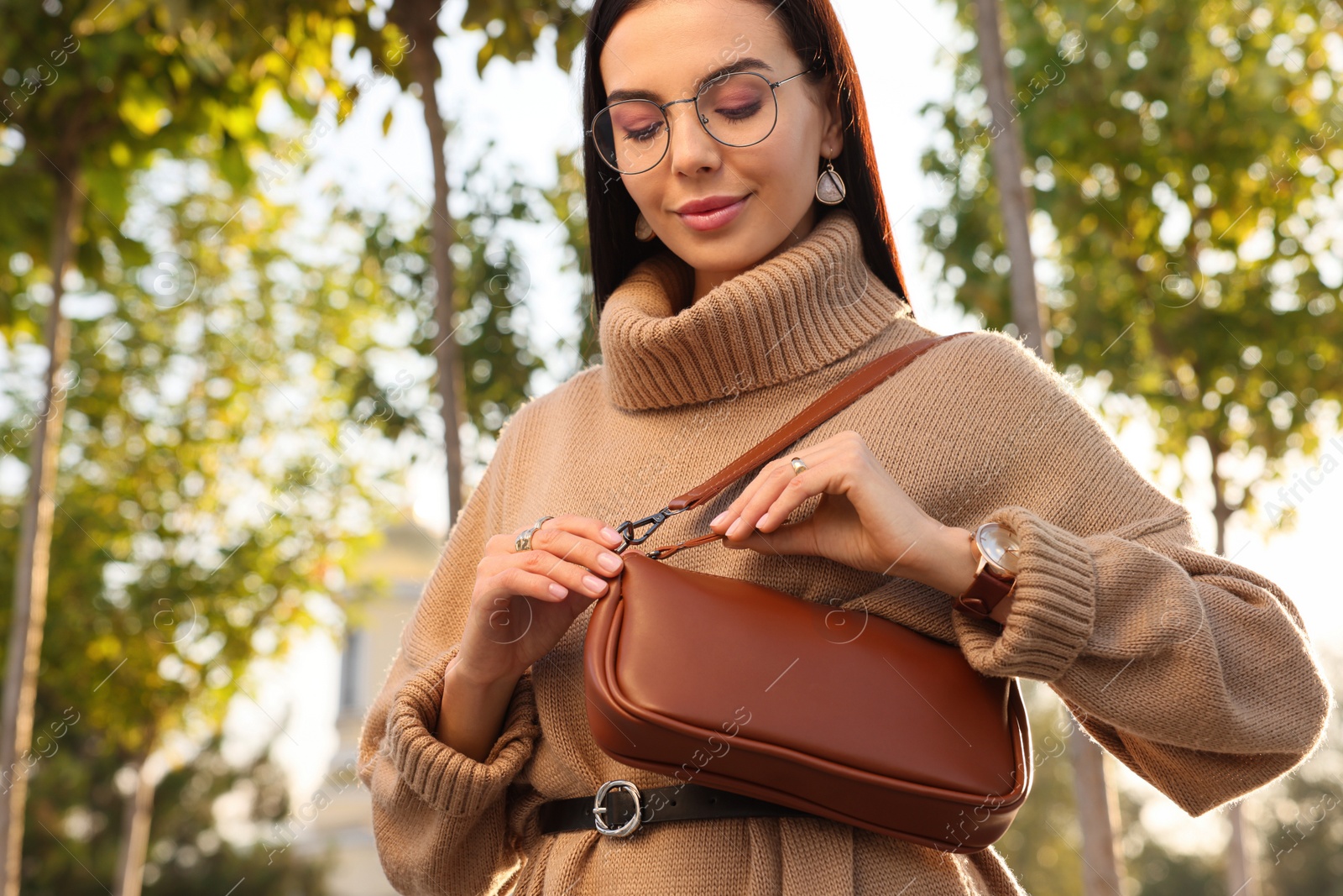 Photo of Fashionable young woman with stylish bag on city street