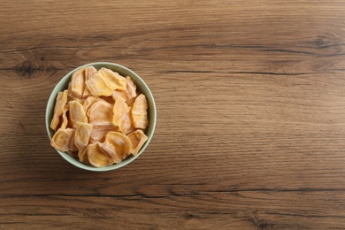 Delicious dried jackfruit slices in bowl on wooden table, top view. Space for text