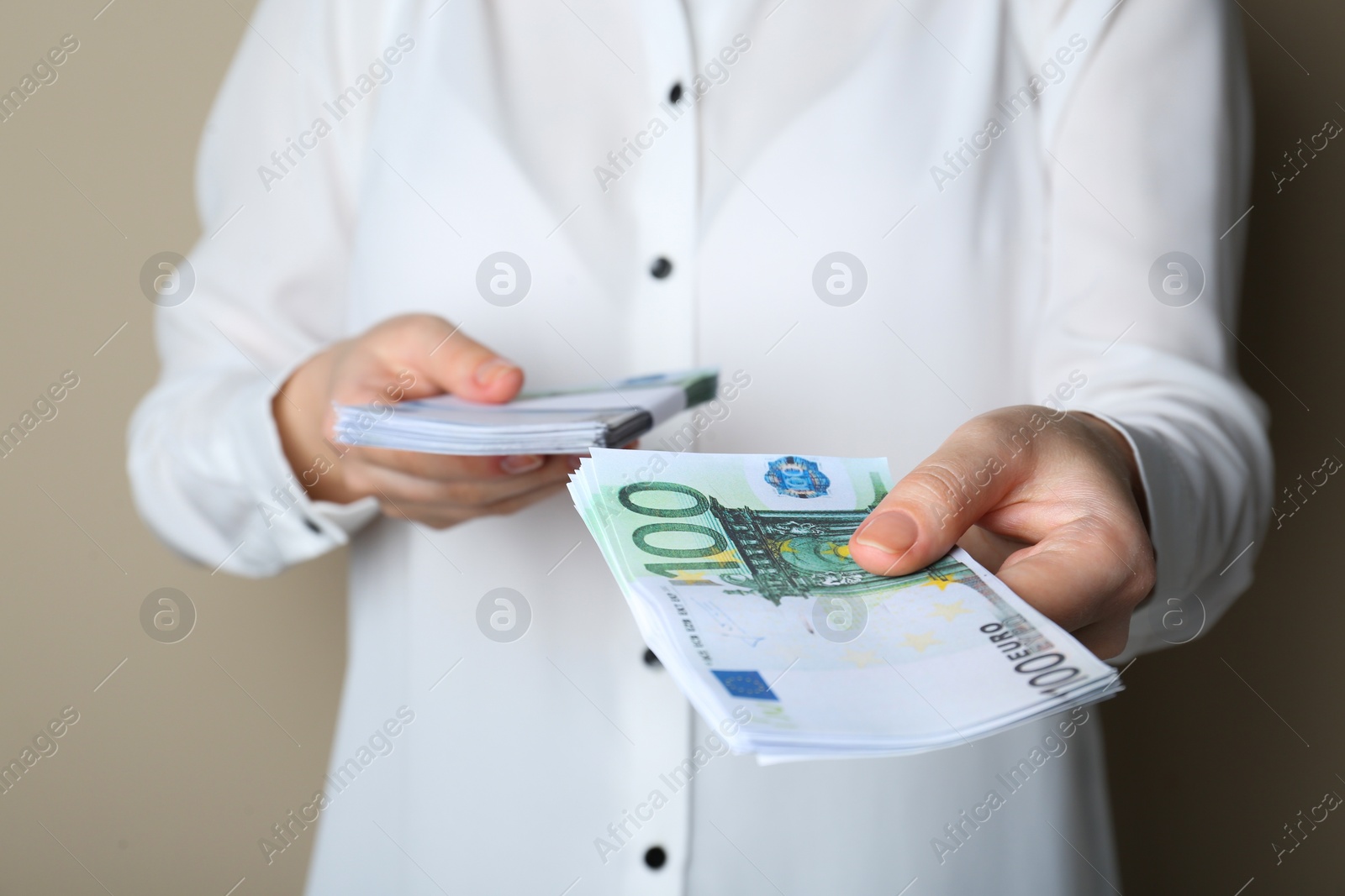 Photo of Woman holding 100 Euro banknotes on beige background, closeup. Money exchange